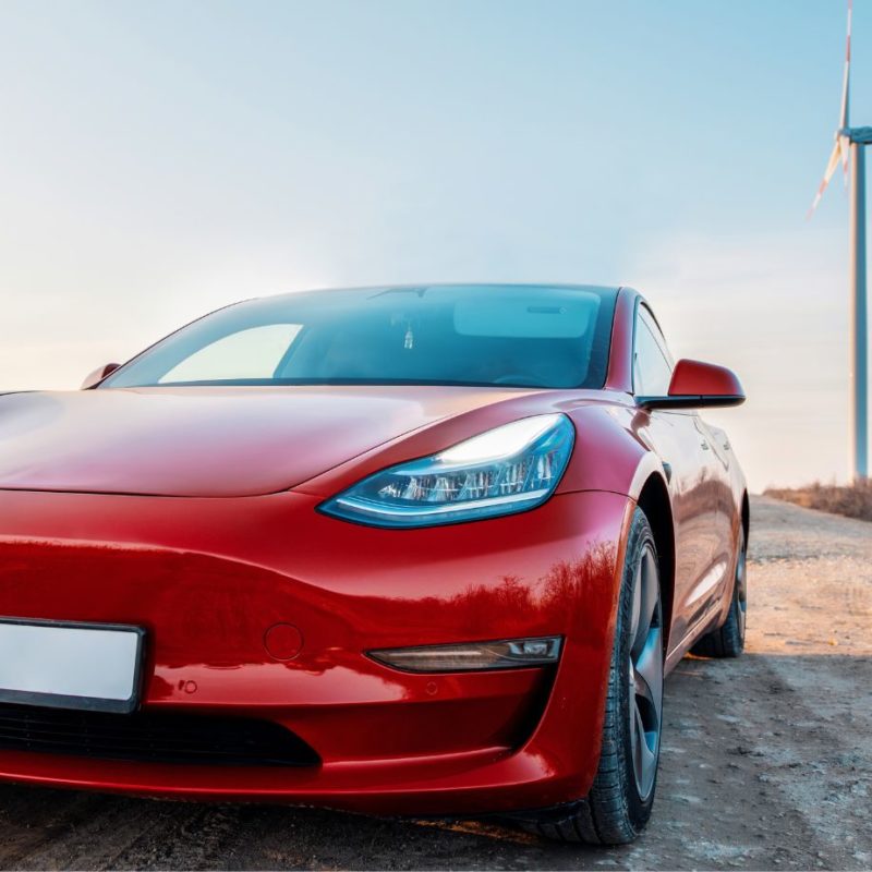 Tesla with a wind turbine in the background