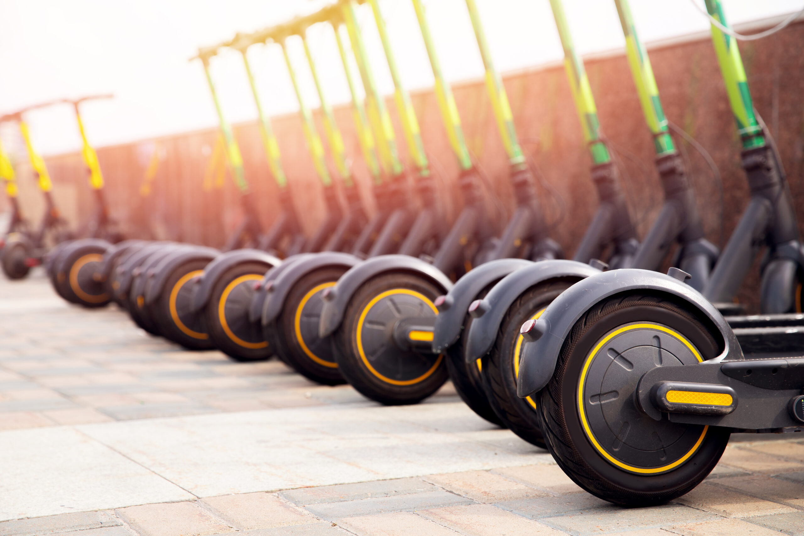 Row of electric scooters parked on a sidewalk.